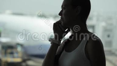 年轻女子在机场带着智能手机，背景是飞机